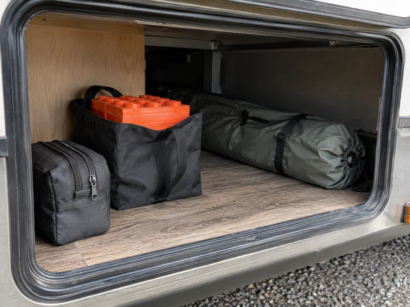 Small setup pouch near an RV hatch with a folding chair bag farther inside