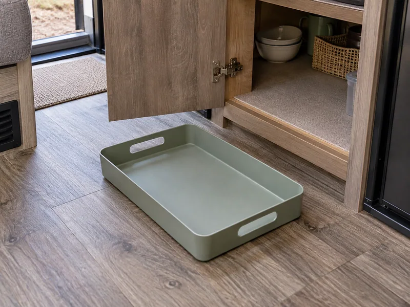 Empty tray beside an RV cabinet opening with visible hinges and threshold